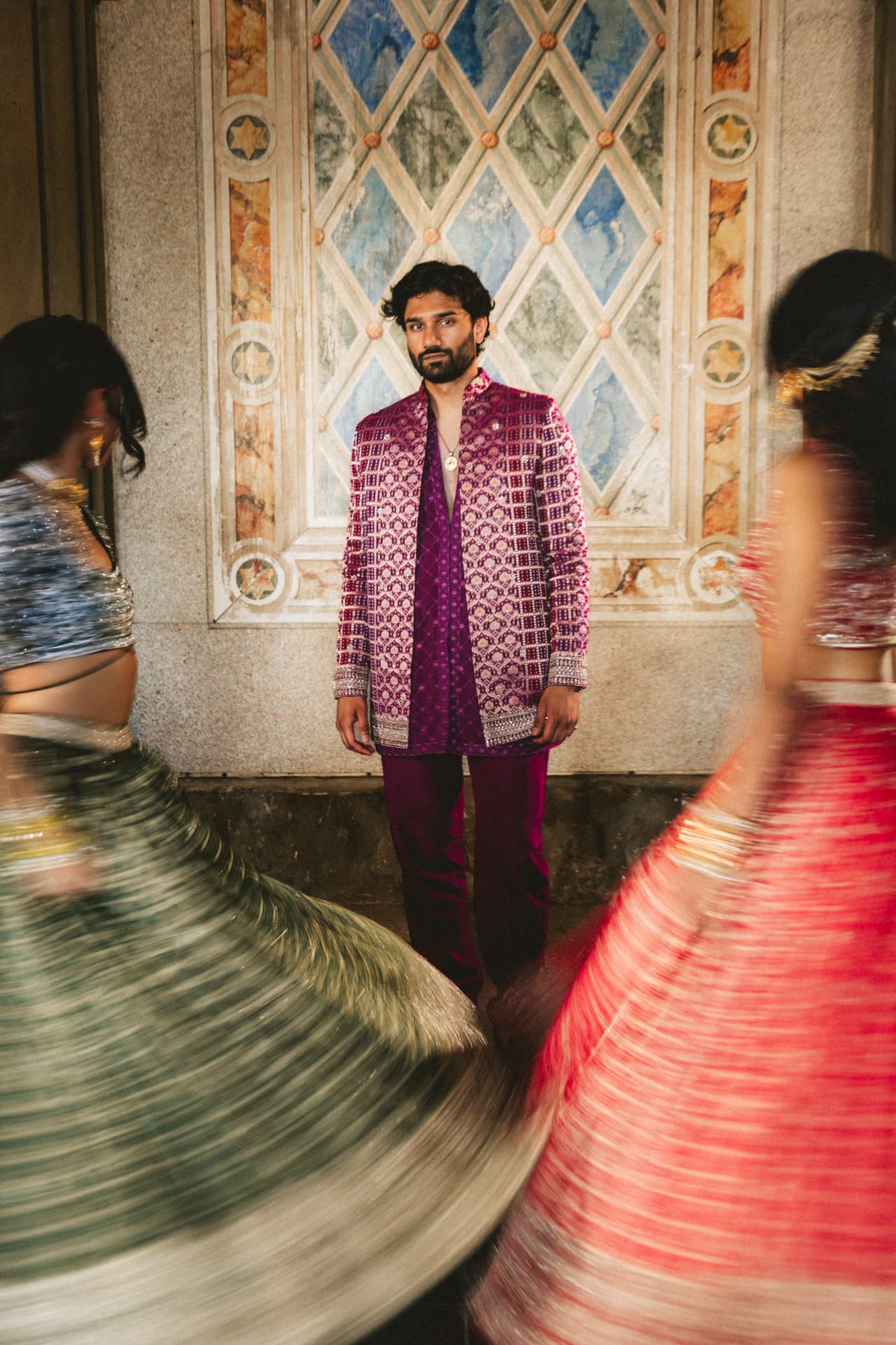 Model in a purple jacket set framed by two spinning lehengas