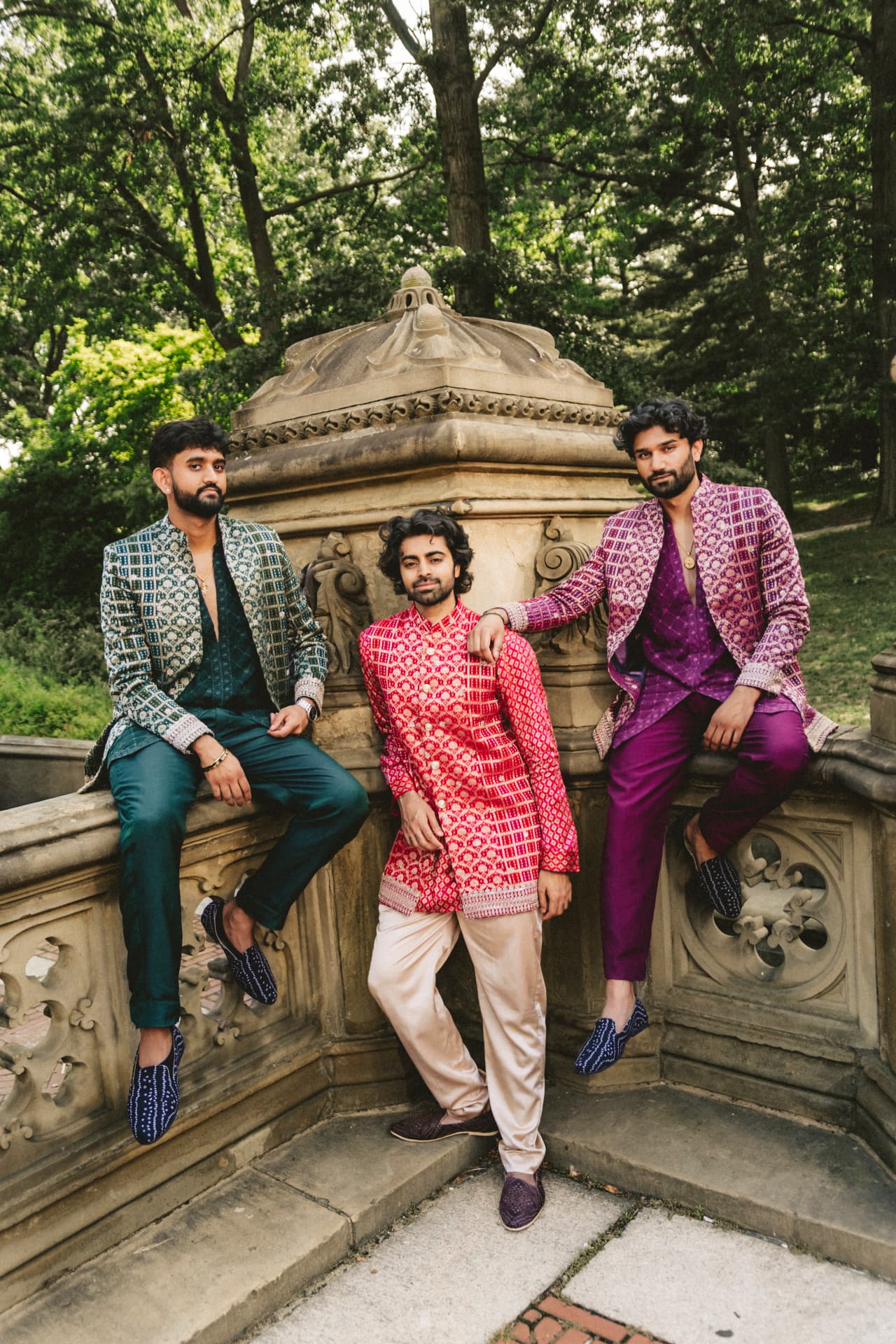 Three models in emerald, red and magenta Rangrez menswear on a stone balustrade