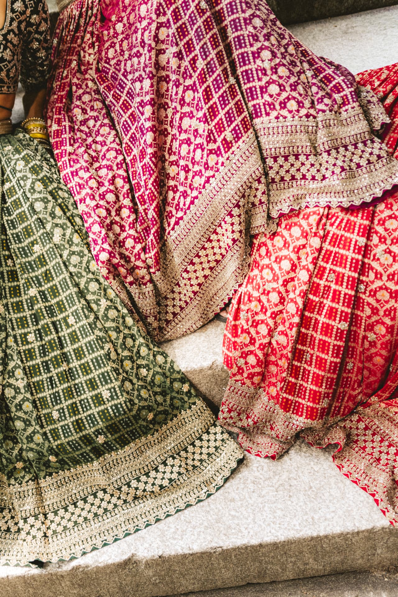 Detail of emerald, magenta and red bandhani skirts with gold scalloped borders